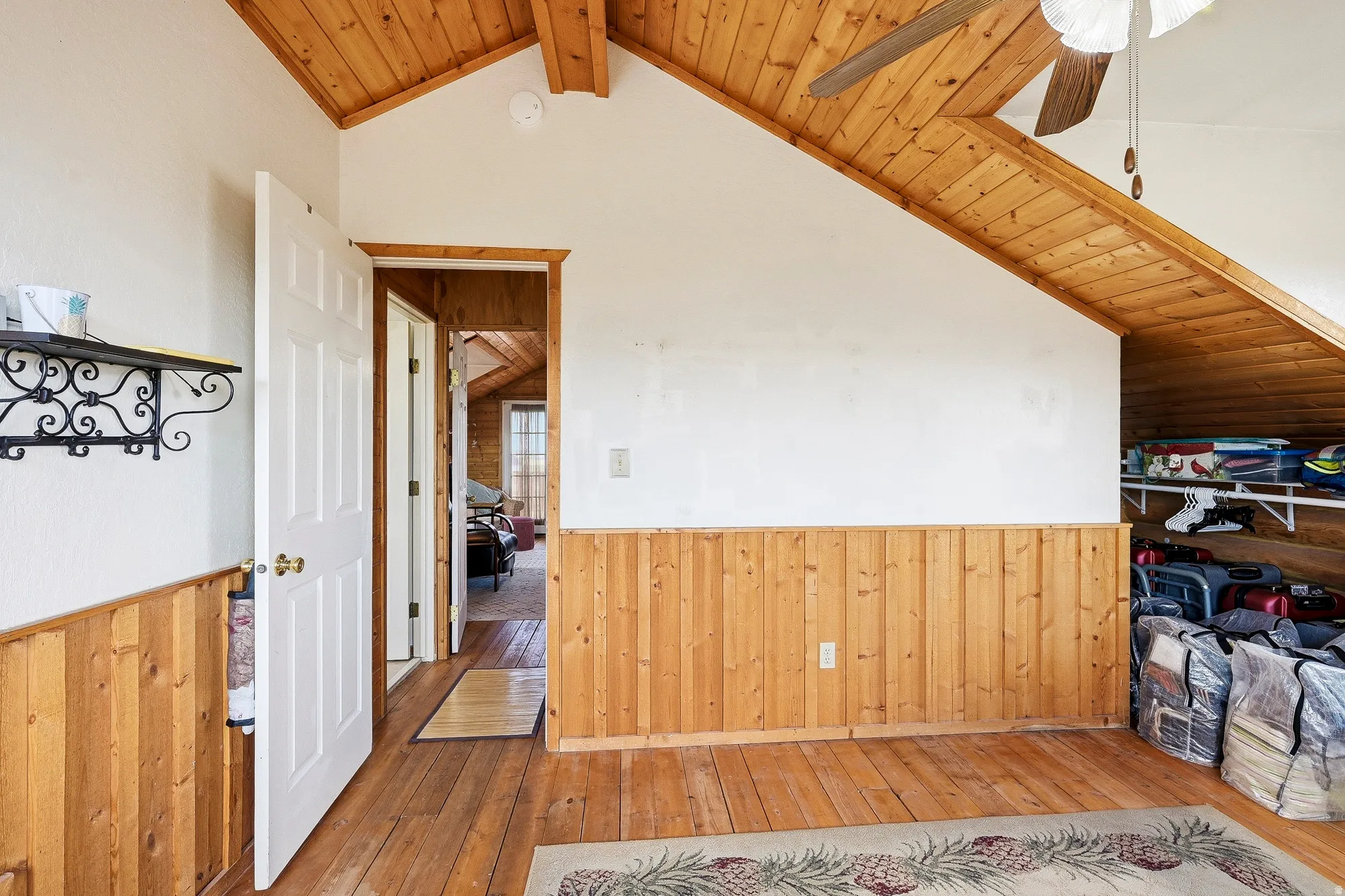 Interior space featuring wood-finish flooring, wainscoting, and an angled wood-finish ceiling