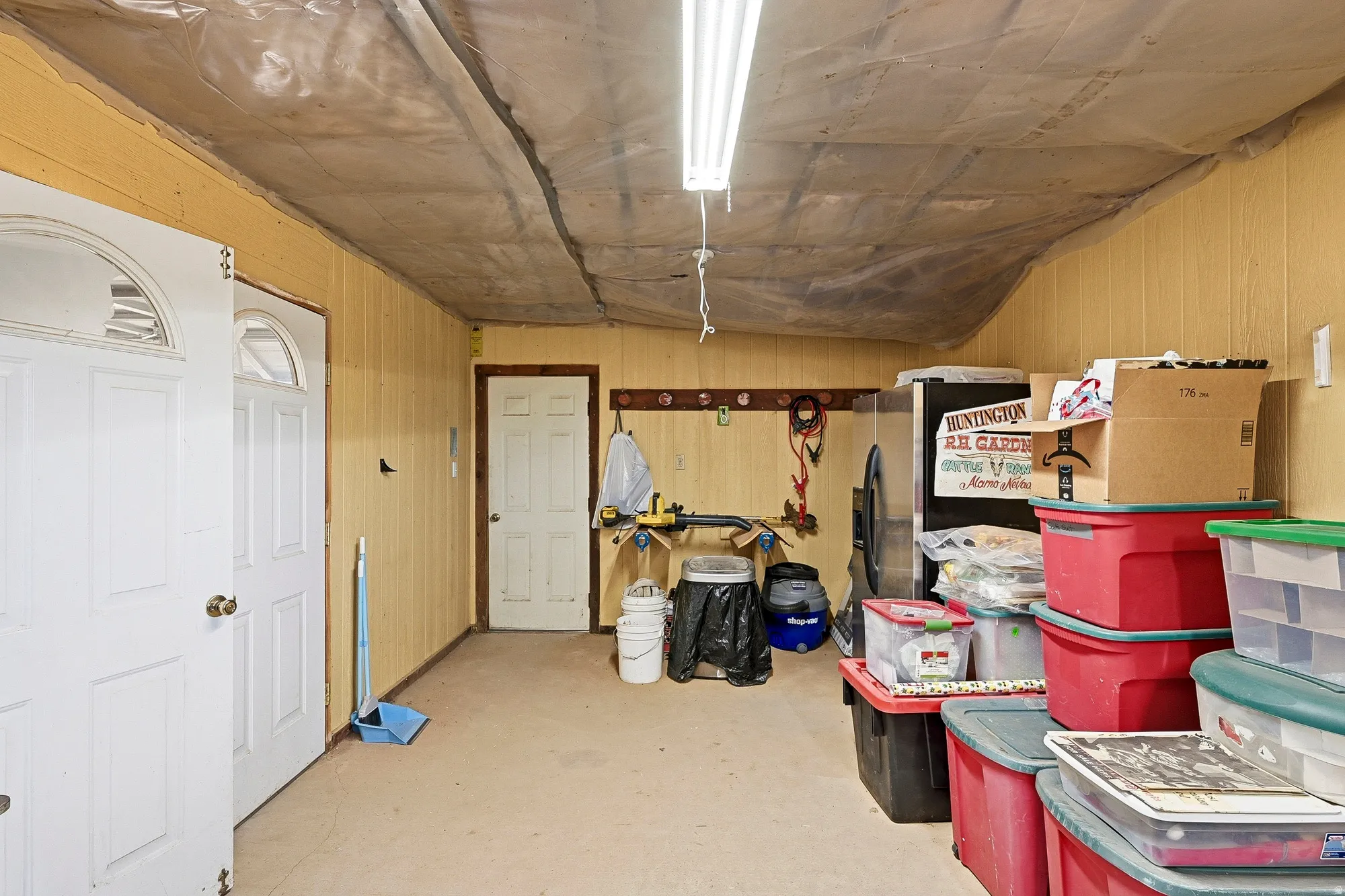 Utility room featuring beadboard paneling, two white paneled doors, and a workbench area
