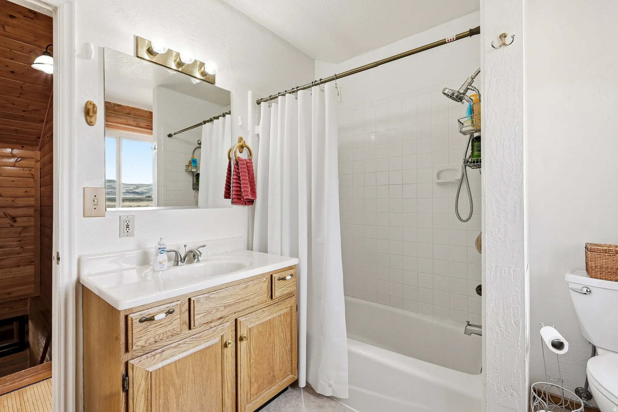 Full bathroom featuring a single vanity with wood-finish cabinetry, white countertop, and integrated sink