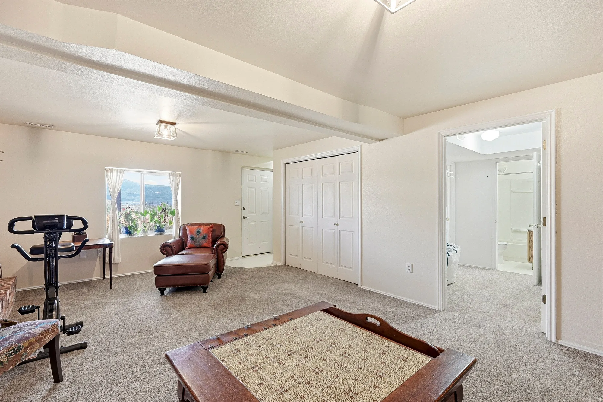 Spacious room featuring neutral carpeting, a large window, and white bi-fold closet doors