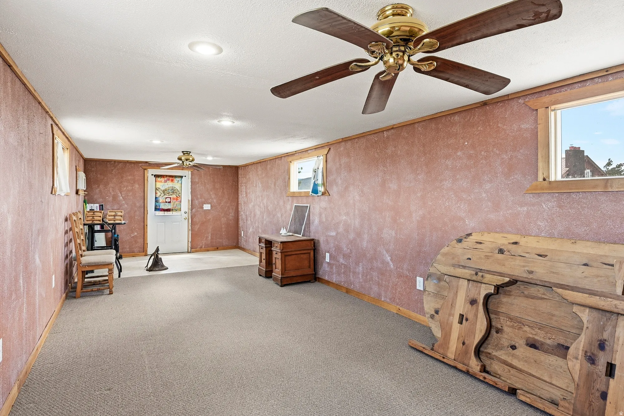Spacious lower level room featuring recessed lighting and two ceiling fans with brass accents
