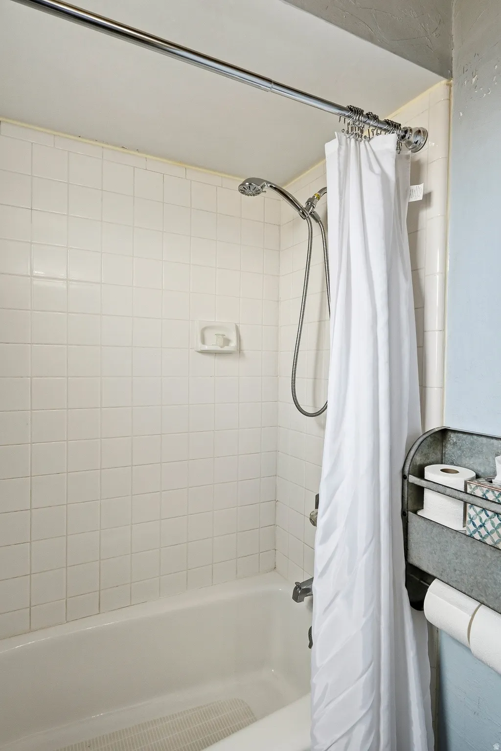 Bathtub with white tile surround and shower fixtures