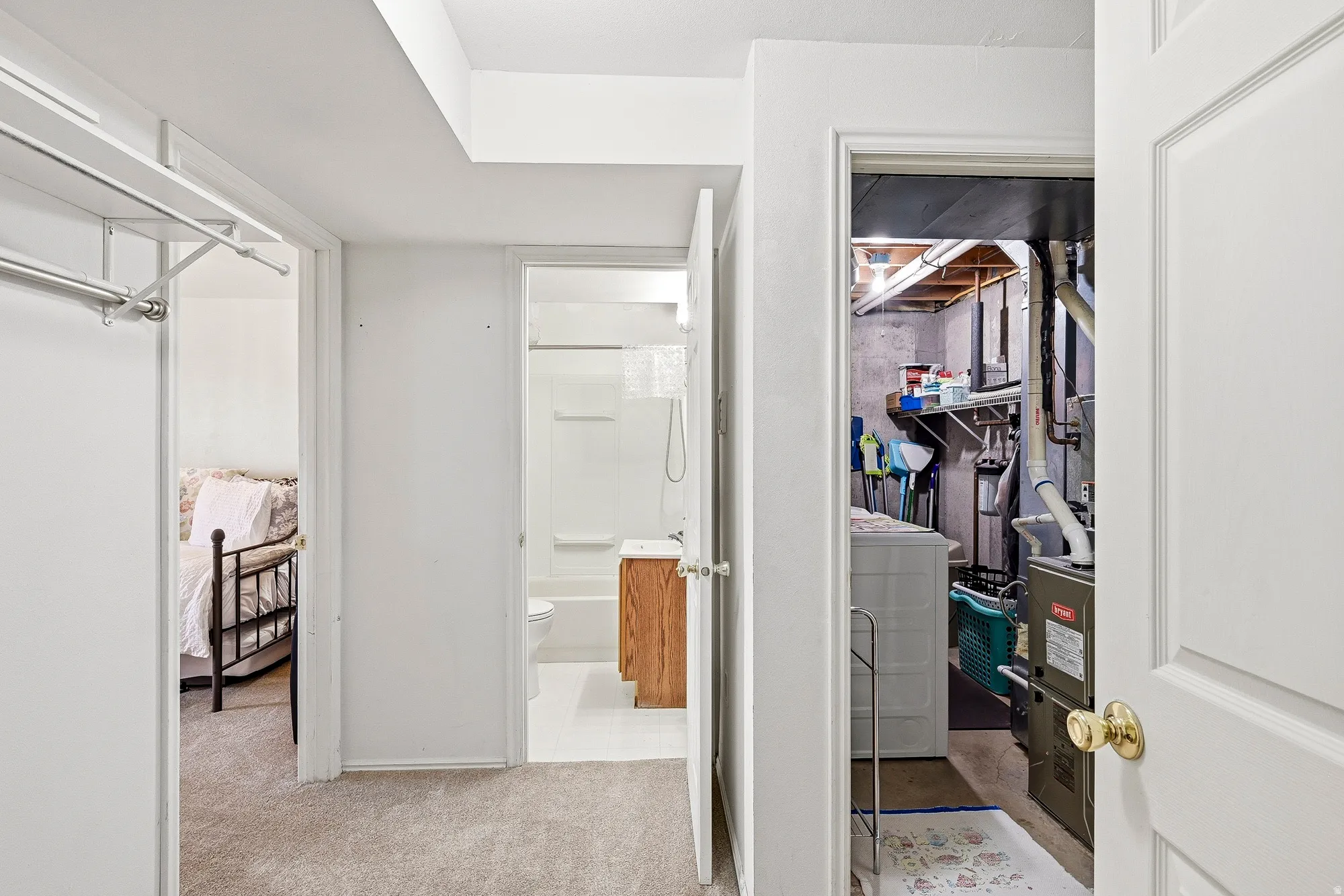Carpeted hallway offering access to a bedroom, a bathroom, and a utility room