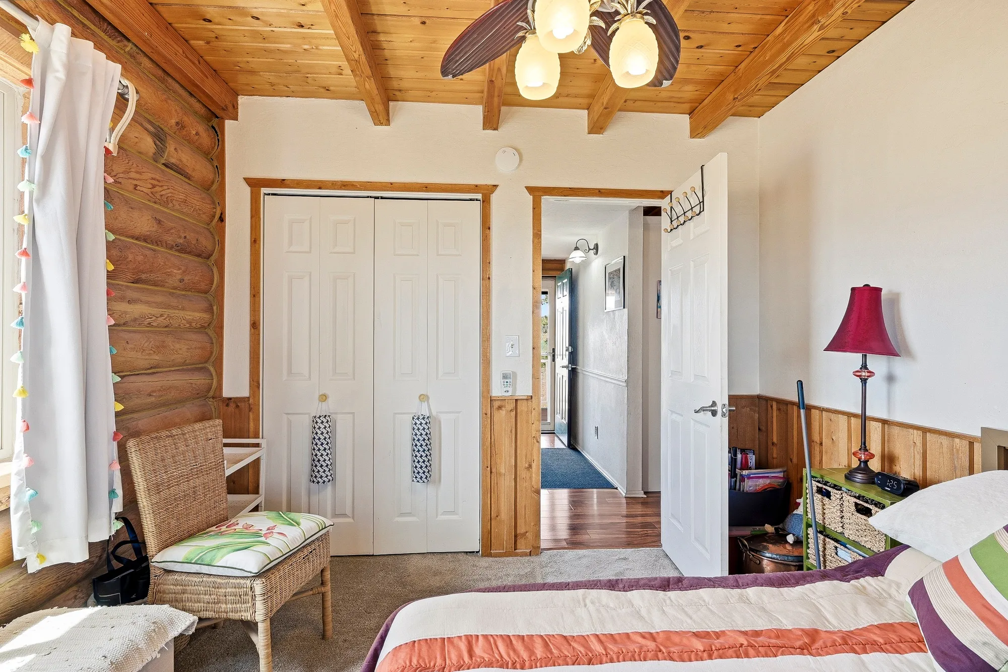 Interior room featuring exposed wood log walls, a wood-paneled ceiling with exposed beams, and a ceiling fan with integrated lighting