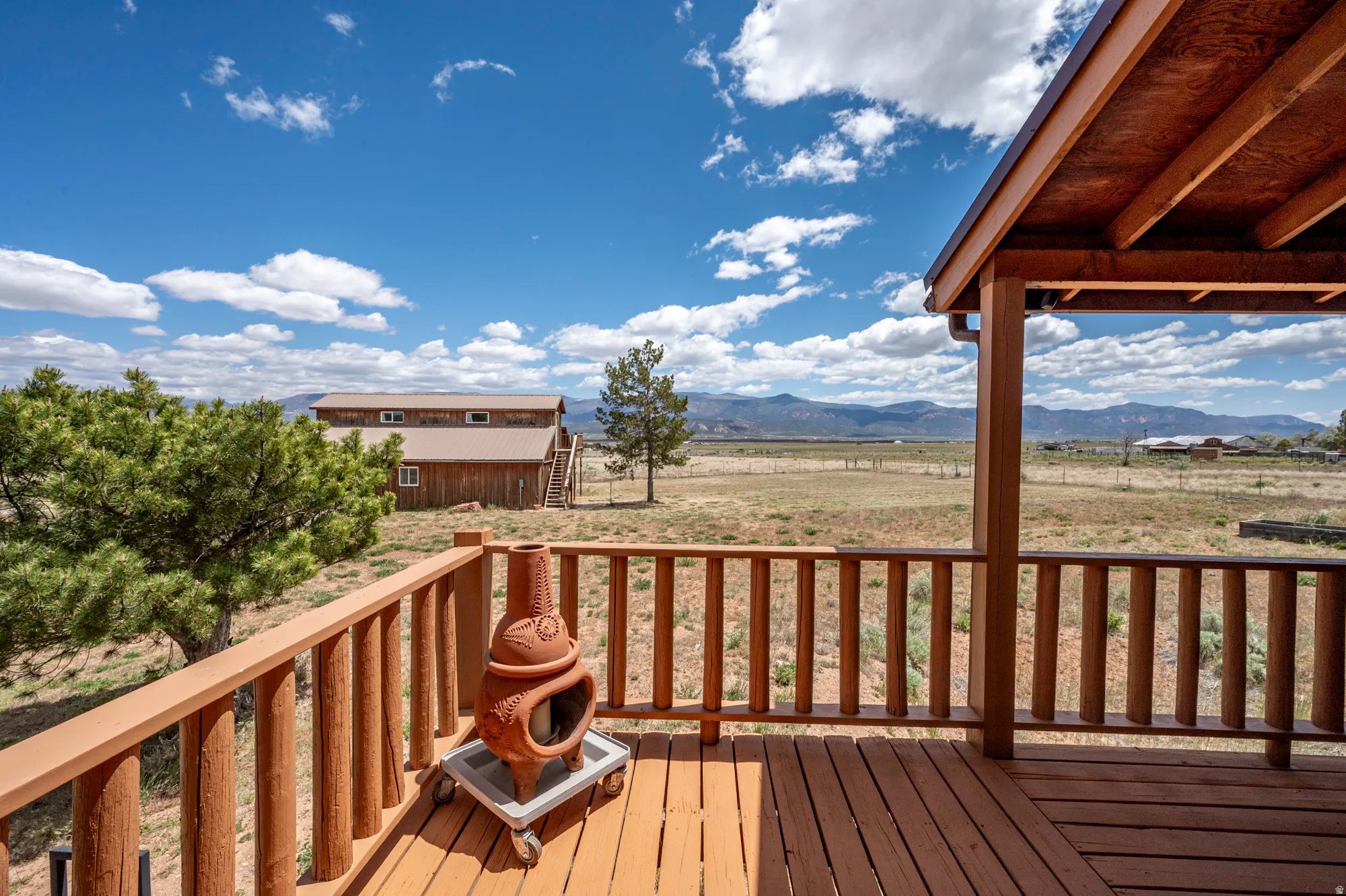 Expansive wooden deck featuring rustic log railings and a partial overhead covering