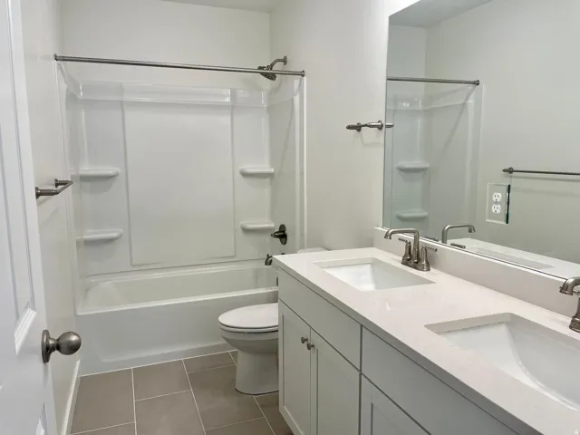 Bathroom featuring a double vanity with integrated sinks and a spacious mirror
