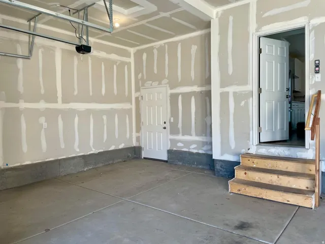 Spacious garage featuring a concrete floor, exposed drywall, and an overhead door system