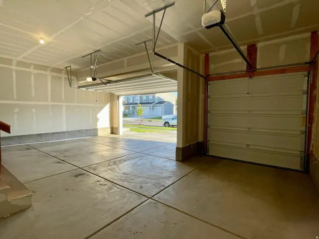Two-car garage featuring concrete flooring, automatic garage door openers, and an exposed wood staircase