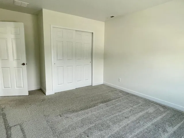 Room featuring light-colored walls and plush gray carpeting