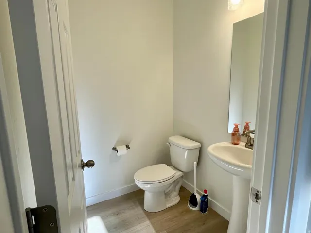 Powder room featuring a pedestal sink, wall-mounted mirror, and wood-finish flooring