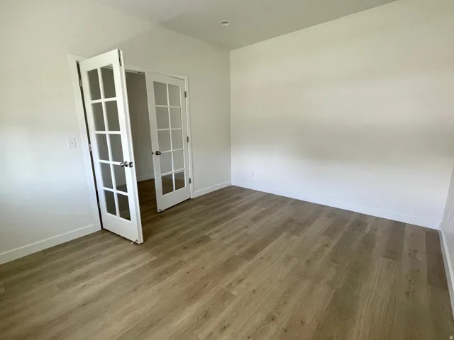 Room featuring wood-finish flooring, white walls, and bright white baseboards