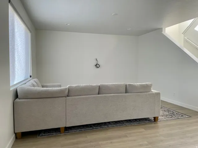 Recessed lighting illuminates the open living space featuring wood-finish flooring and a staircase with white risers and handrails
