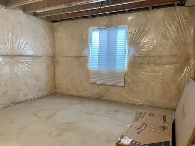 Unfinished basement space featuring exposed wood joists and insulated walls