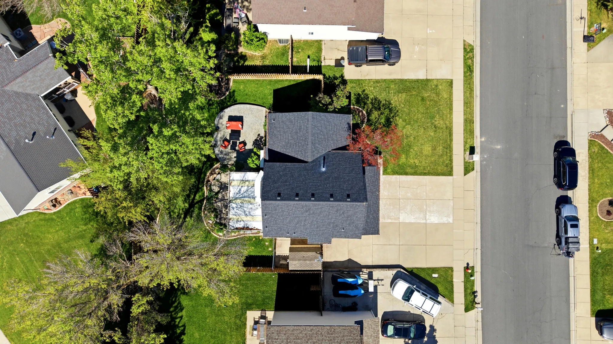 Residential property featuring a dark-shingle roof, extensive paved driveway, and established front lawn
