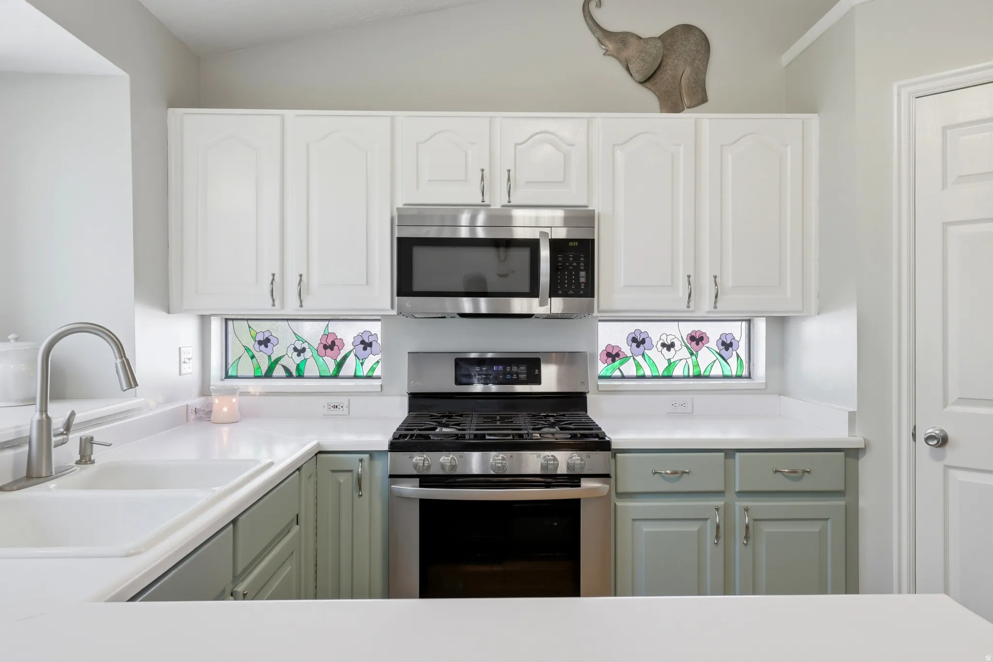 Kitchen featuring white upper cabinetry, sage green lower cabinetry, and white countertops