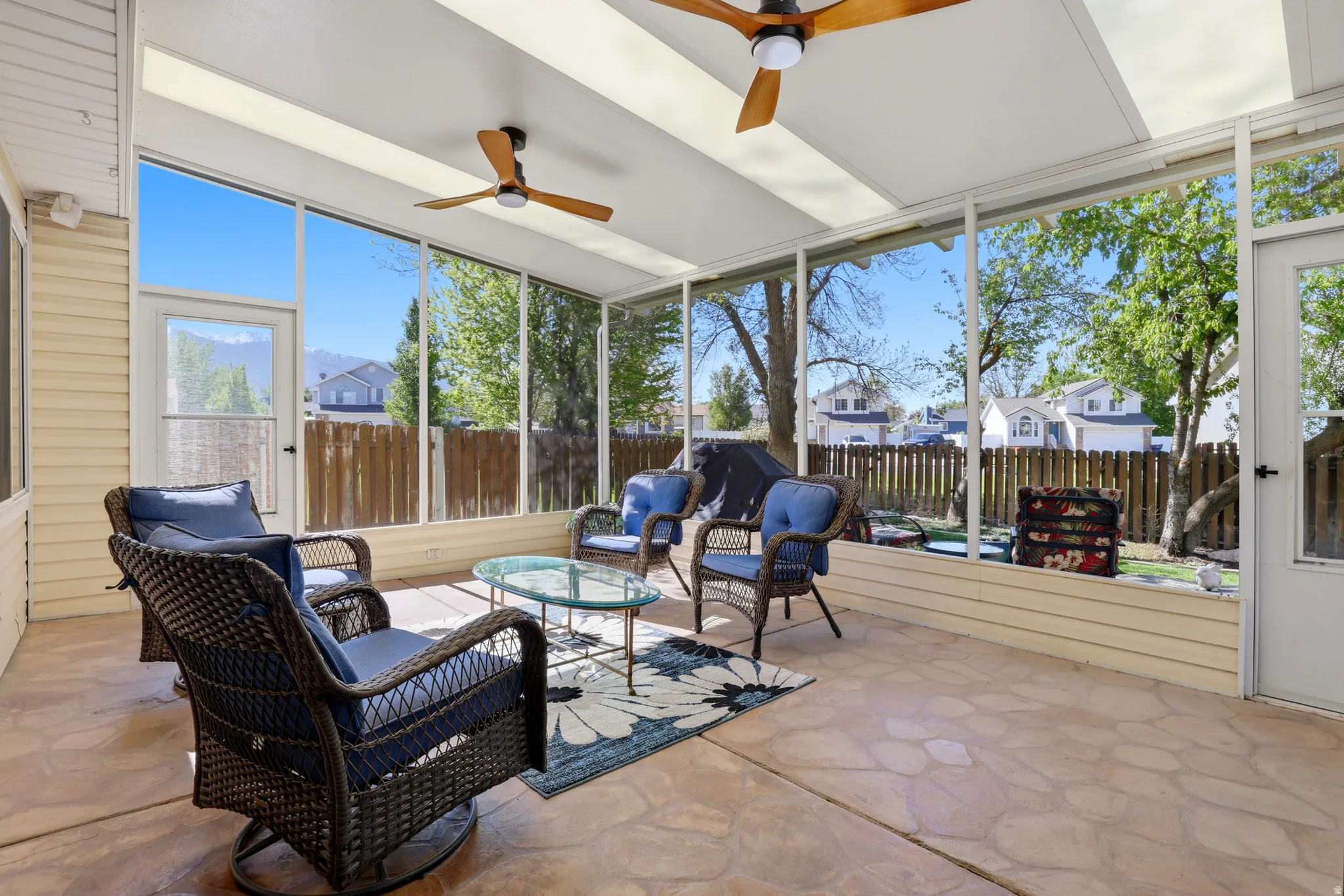 Screened-in patio with stamped concrete flooring, translucent roof panels, and two ceiling fans