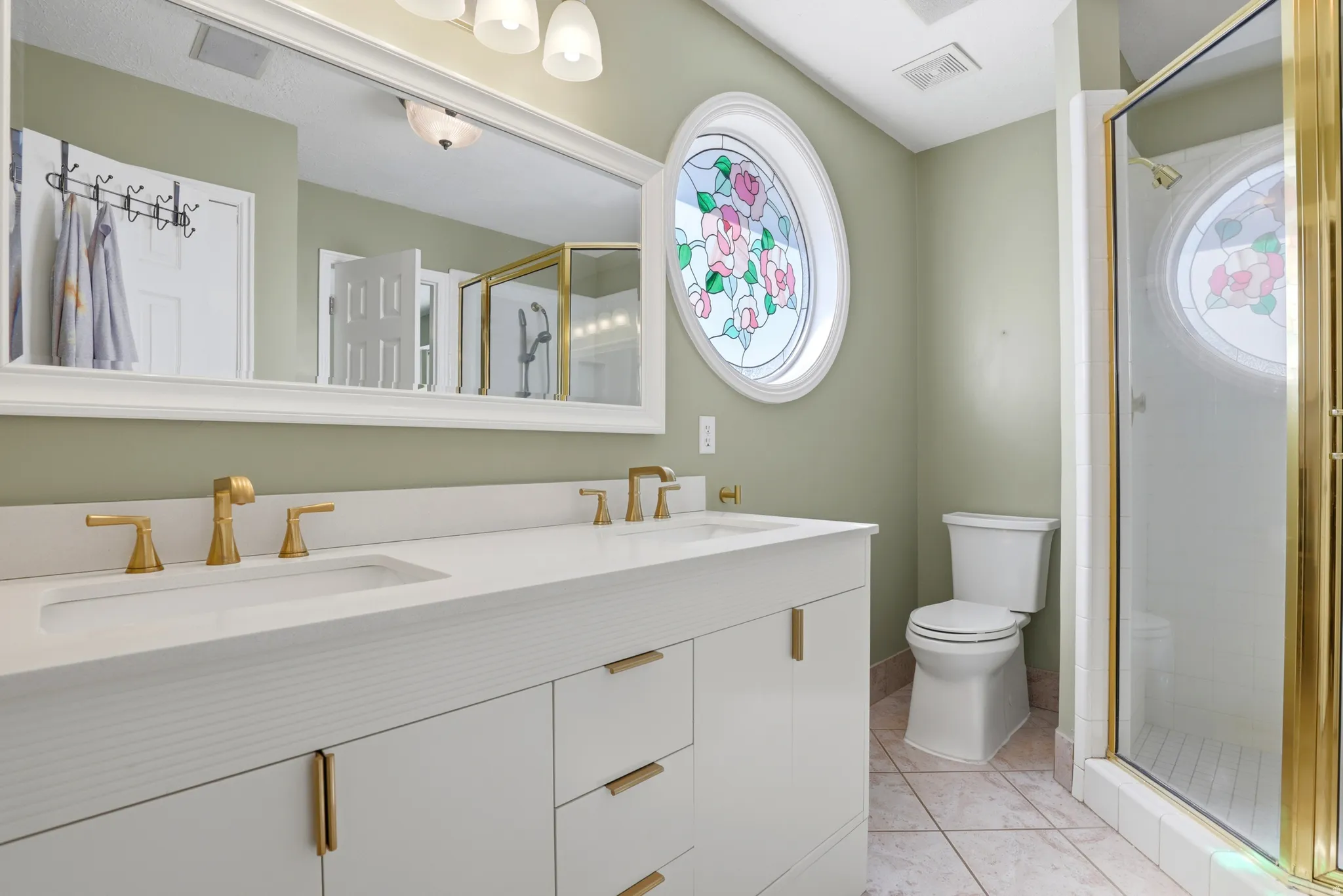 Master bathroom. Dual vanity with integrated white sinks, accented by gold-finish fixtures and white cabinetry