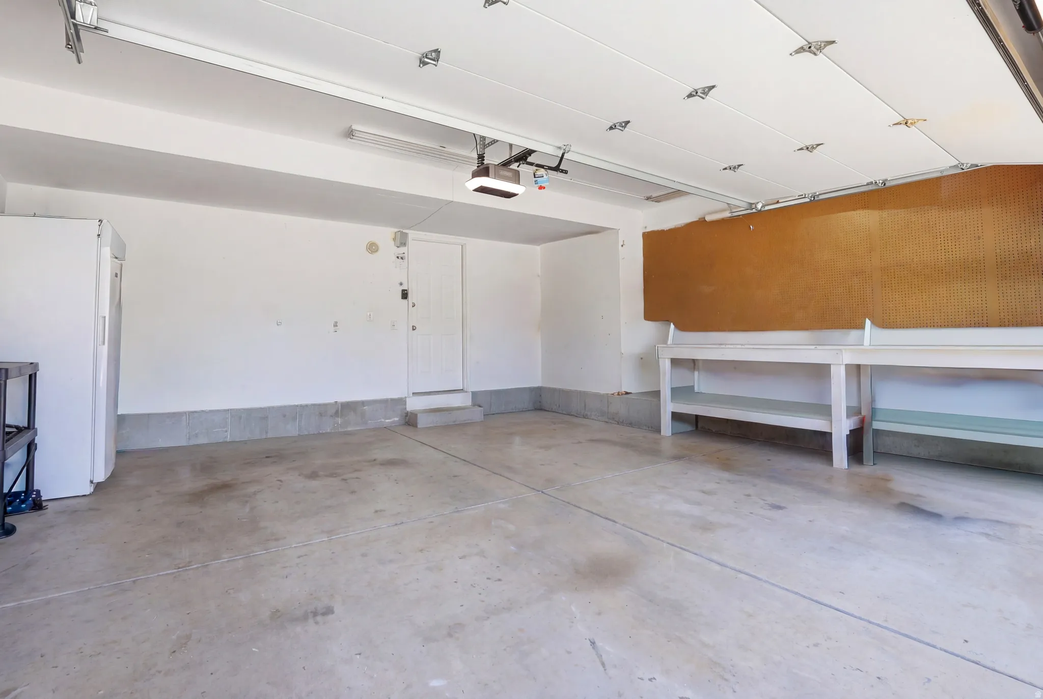Spacious garage featuring a concrete floor, white walls, built-in shelving, and an automatic garage door opener