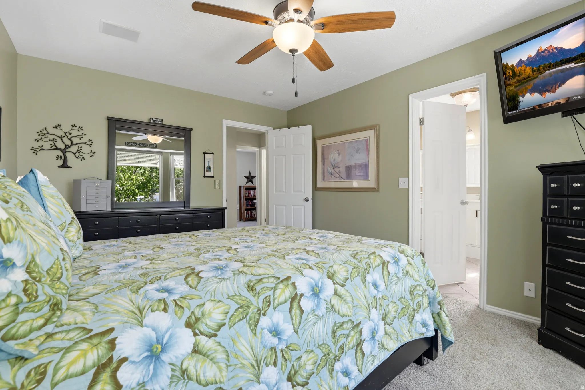 Carpeted room featuring a ceiling fan with light fixture, green wall paint, and white trim