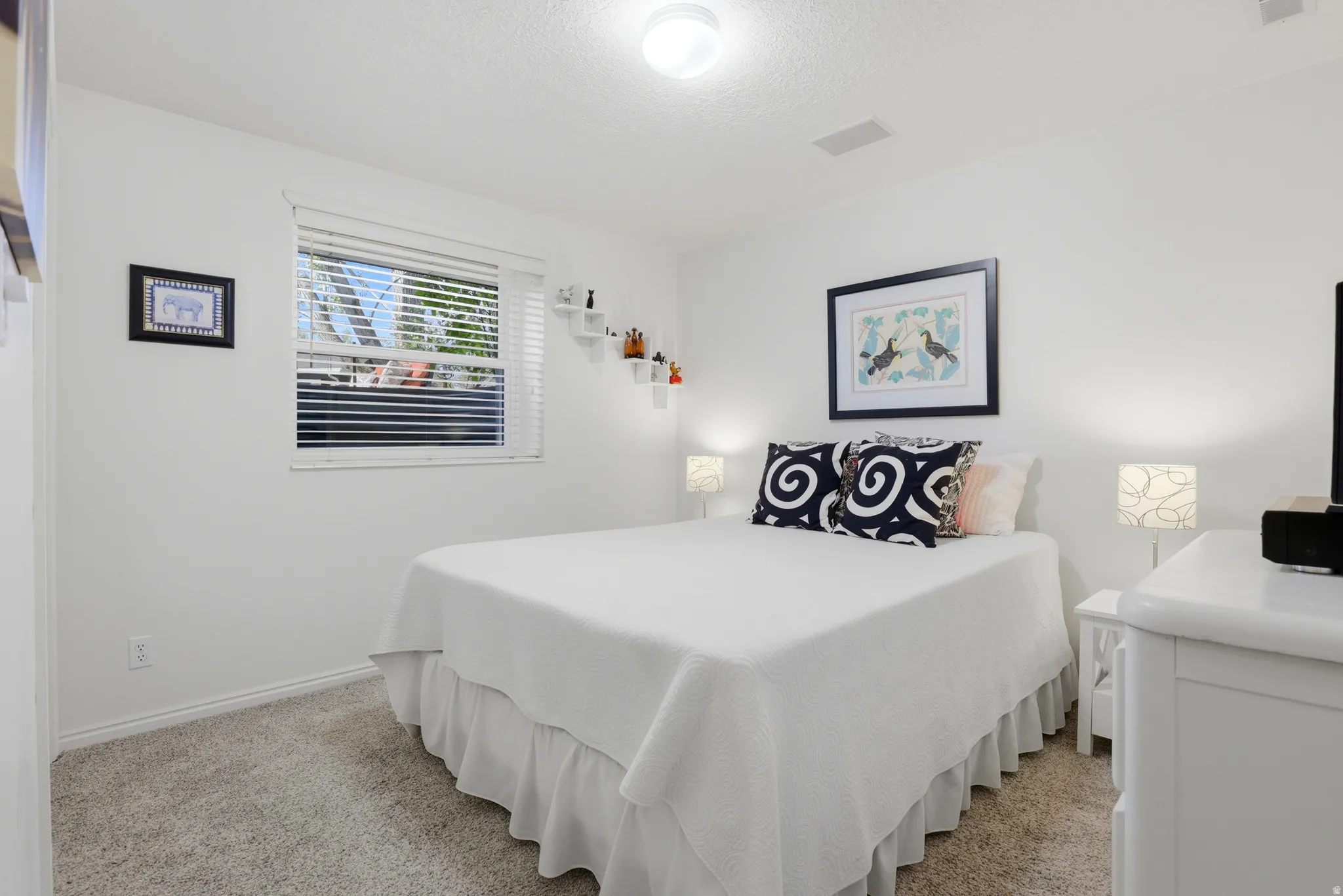 Basement Carpeted bedroom featuring a single window with blinds, white painted walls, a flush-mount ceiling light fixture, and a single built-in ceiling speaker