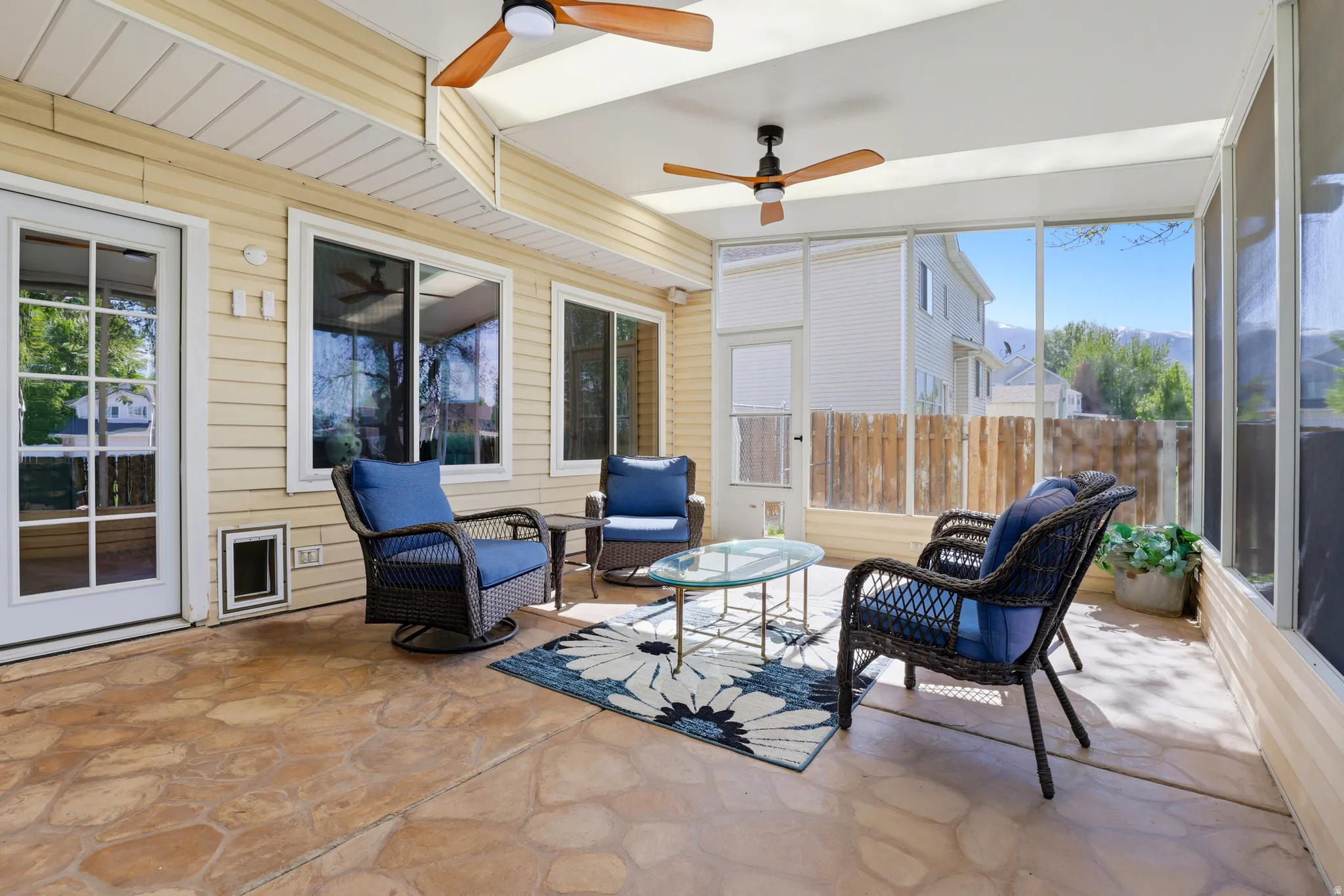 Screened porch featuring stamped concrete flooring, three ceiling fans with light fixtures, and exterior vinyl siding