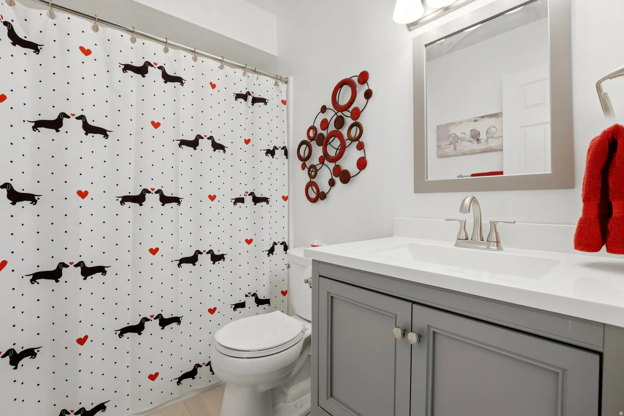 Hallway Bathroom featuring a gray vanity with an integrated sink, brushed nickel faucet, and a framed mirror