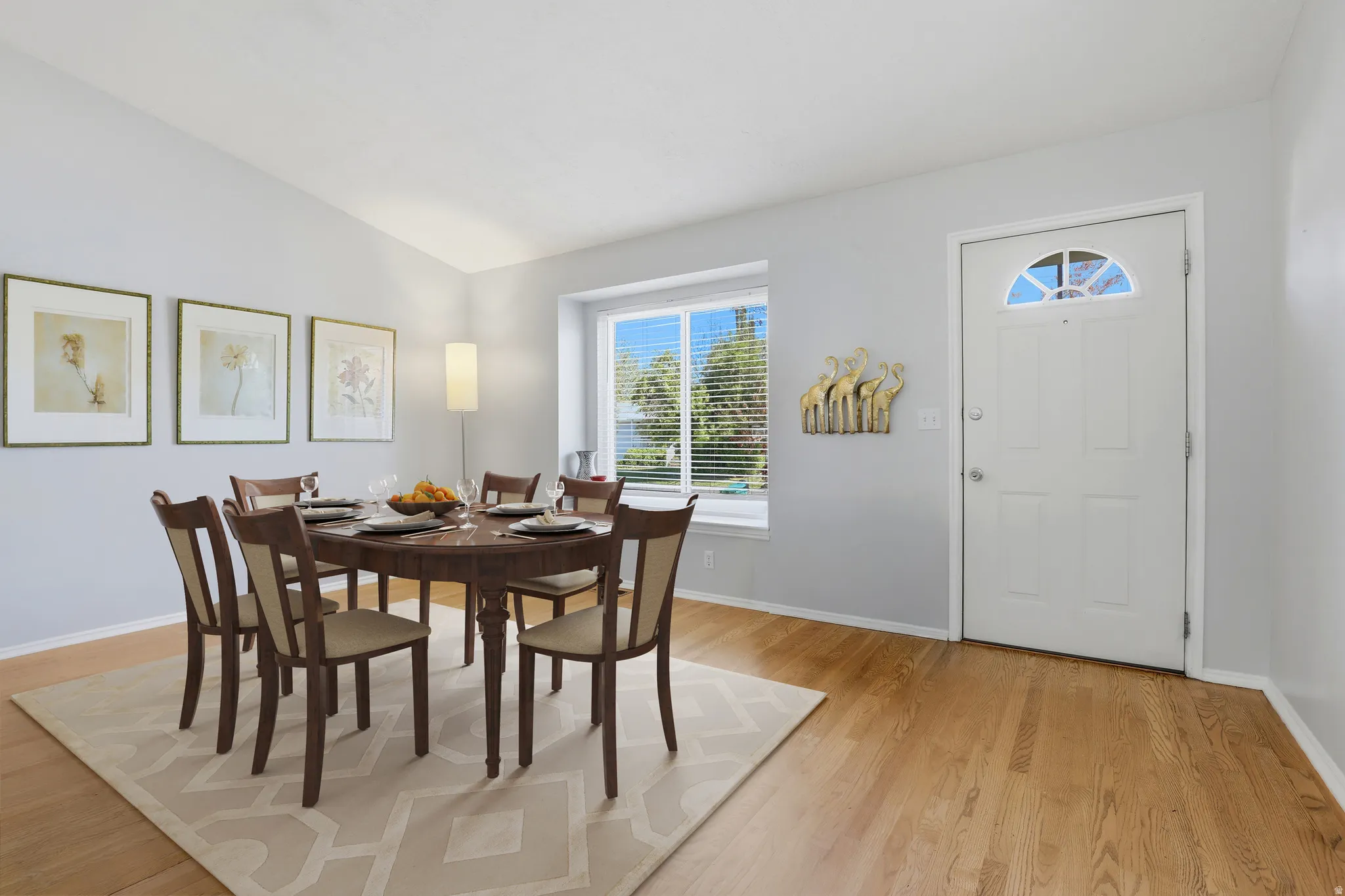 Spacious interior featuring wood-finish flooring, a vaulted ceiling, and a large window with white blinds