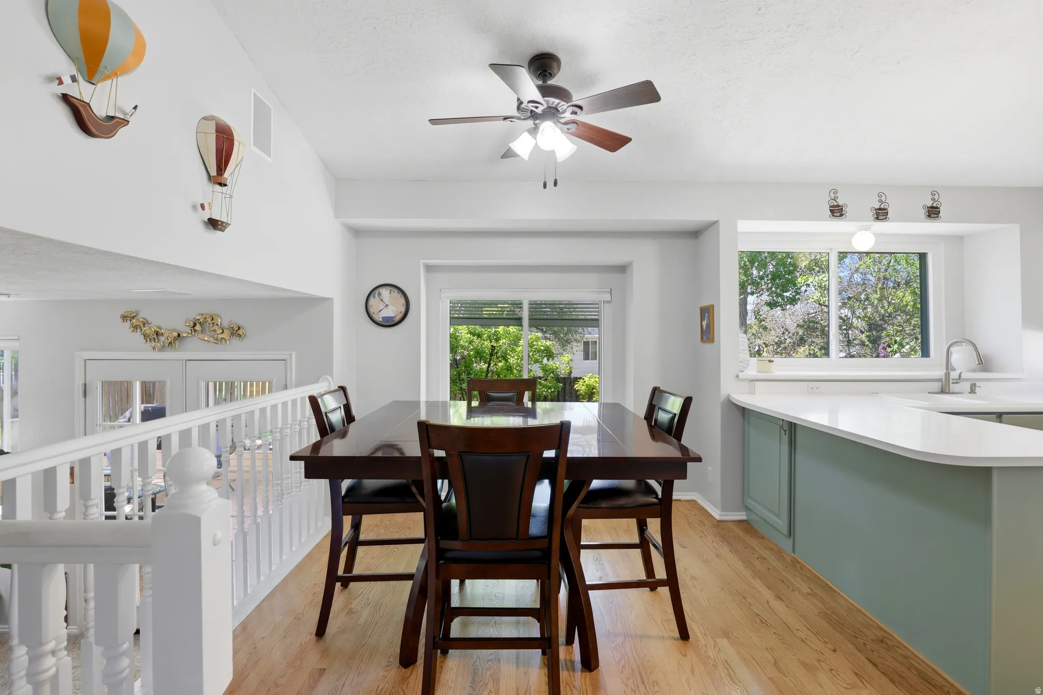 Open-concept dining area featuring wood-finish flooring, a contemporary ceiling fan, and abundant natural light from multiple windows