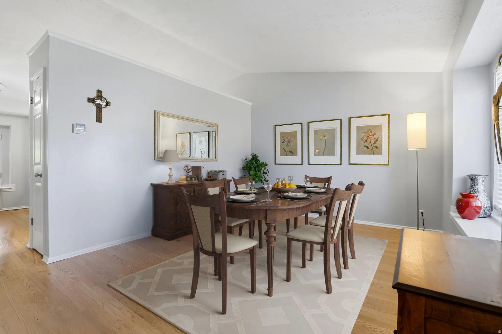 Open-concept dining area featuring wood-finish flooring, a neutral wall palette, and crown molding