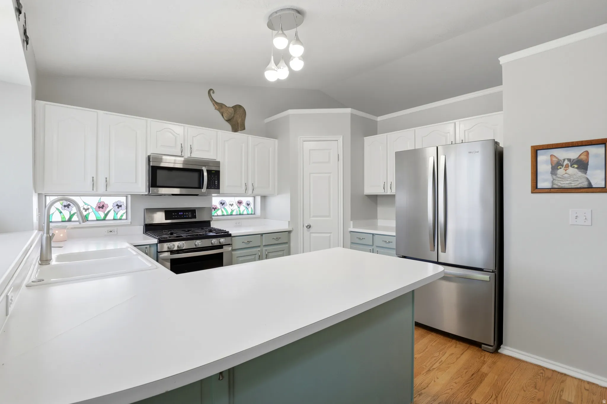 Kitchen featuring white upper cabinetry, light blue lower cabinetry, and expansive white countertops