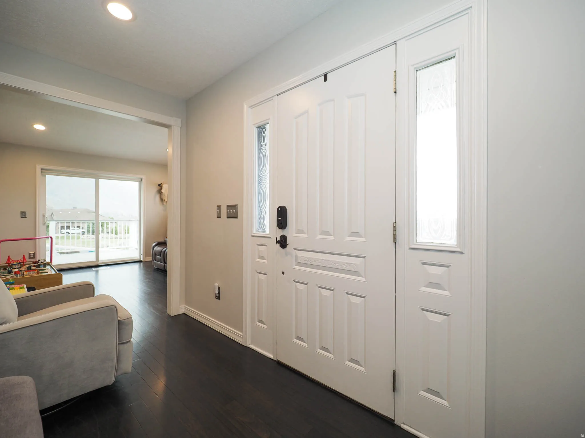 Welcoming Entryway Featuring a Paneled White door with Decorative Glass and Beautiful Dark Wood-Finish Flooring.