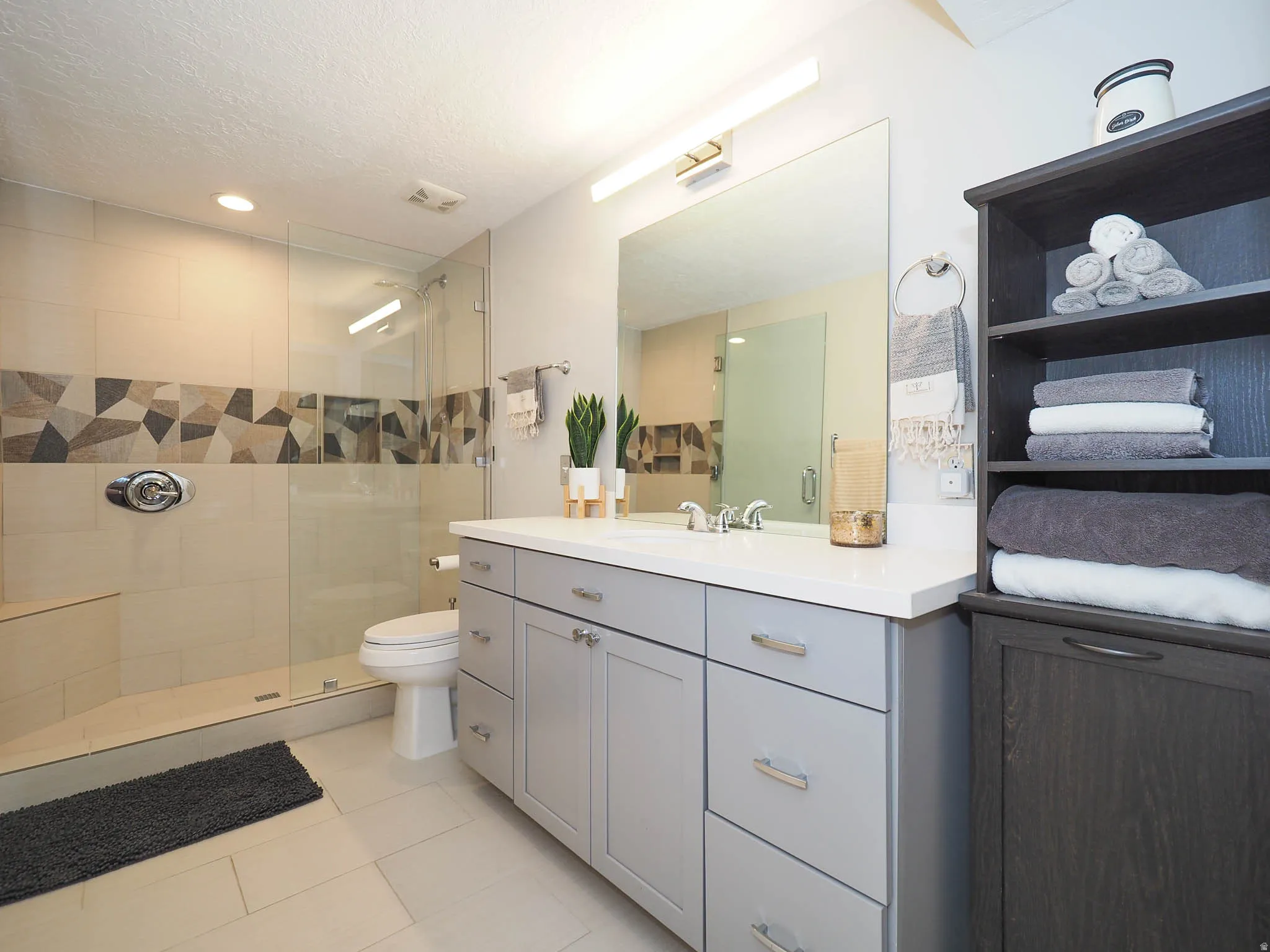 Beautifully Remodeled Bathroom Featuring a Lovely Glass-Enclosed Shower with Attractive Mosaic Accent Band, Stylish Light Gray Cabinetry, Lush White Silestone Countertop, & More!