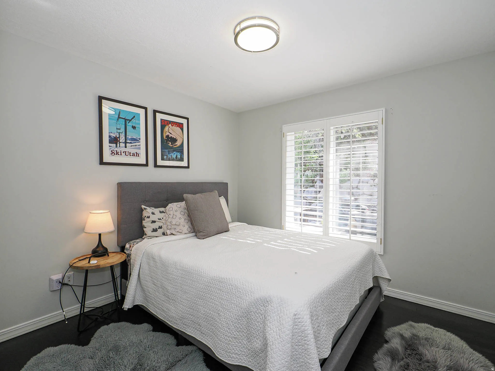 Spacious 2nd Bedroom Featuring Beautiful Wood-Finish Flooring, Lovely Painted Walls, Plantation Shutters, and a Contemporary Ceiling Light