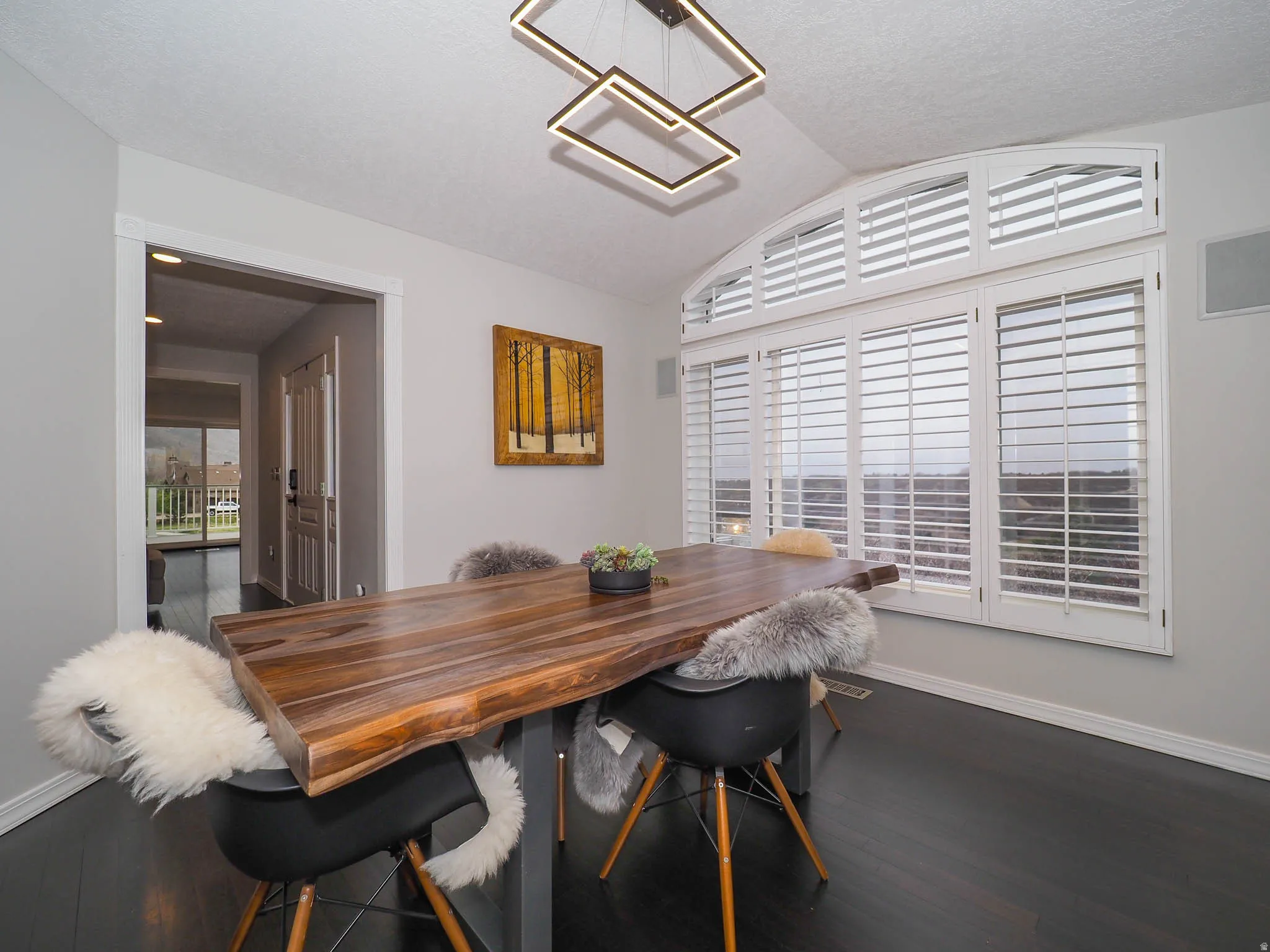 Immaculate, Stylish Formal Dining Room with Vaulted Ceiling, Large Arched Windows, Gorgeous Views, Plantation Shutters, Beautiful Wood-Finish Flooring, and an Attractive Contemporary Ceiling Light Fixture!