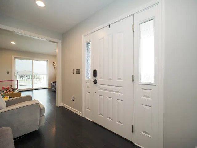 Welcoming Entryway Featuring a Paneled White door with Decorative Glass and Beautiful Dark Wood-Finish Flooring.