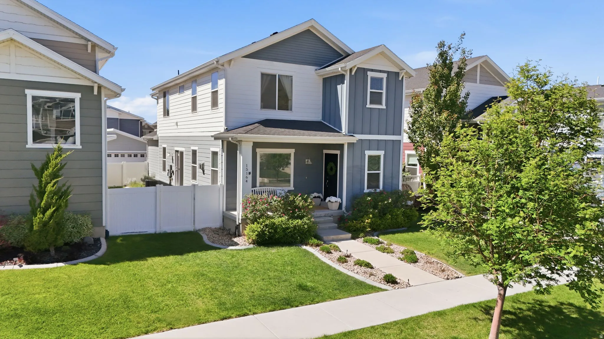 Two-story residence featuring a blue and white exterior, a covered front porch, and a concrete walkway