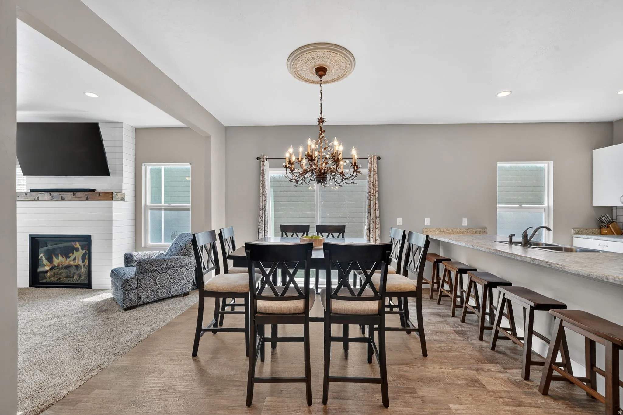 Open-concept living area featuring wood-finish flooring, a contemporary chandelier with a decorative ceiling medallion, and a kitchen island with a light-colored countertop