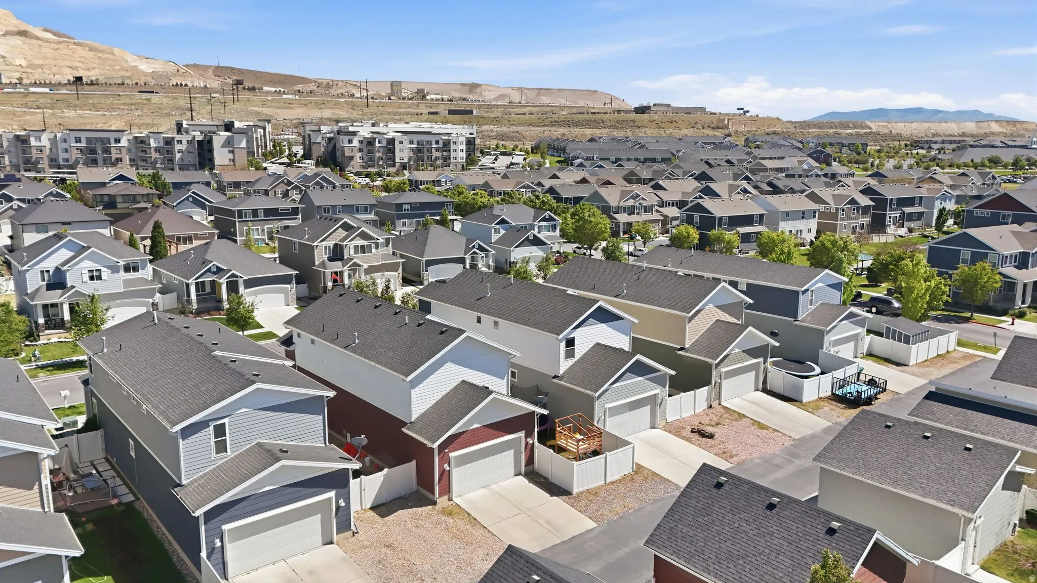 Community featuring multiple residential structures with varied siding colors and pitched roofs, complemented by paved driveways and fenced yard areas