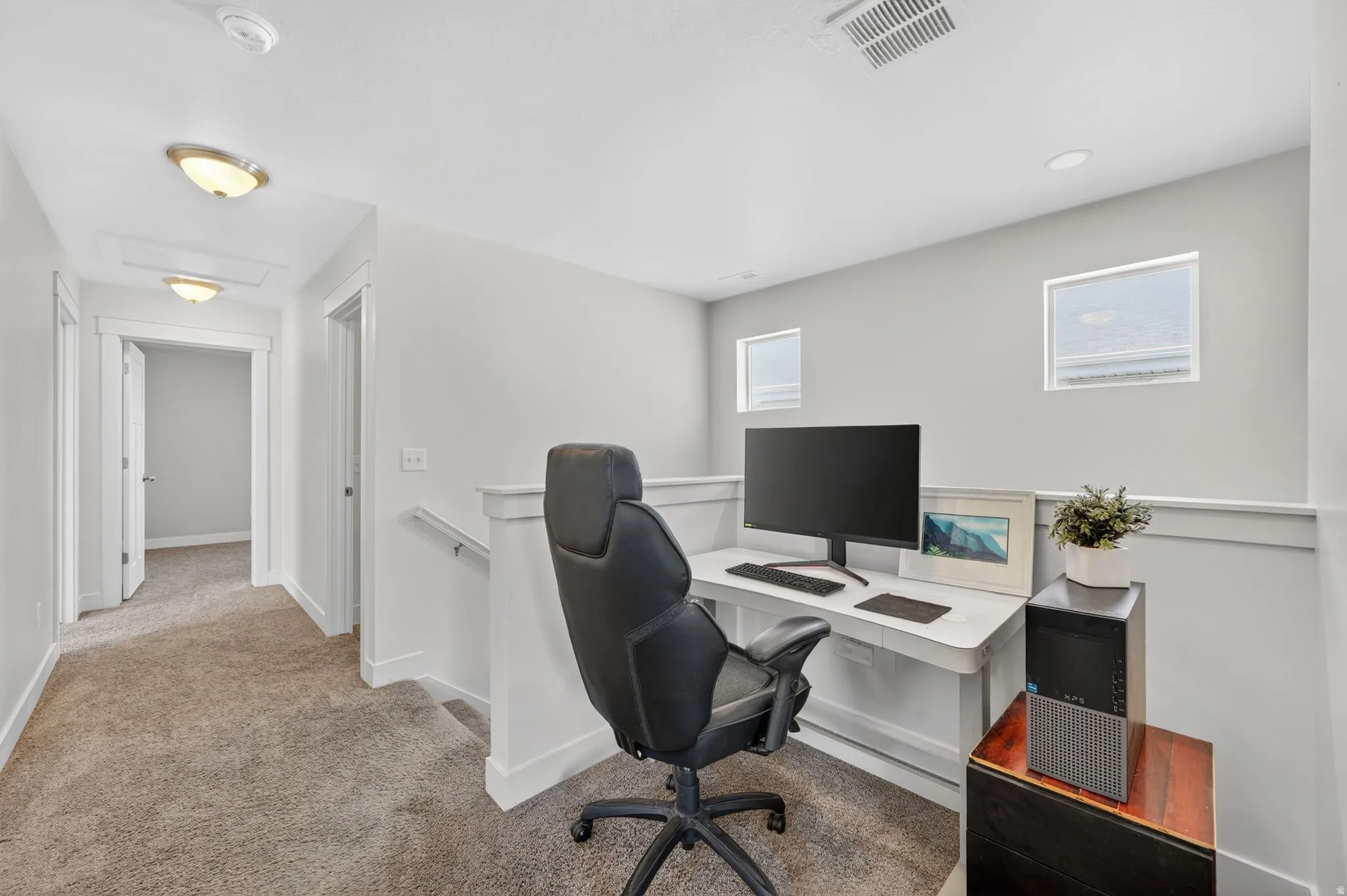 Open loft area featuring two transom windows, light gray wall paint, white trim, and a carpeted floor