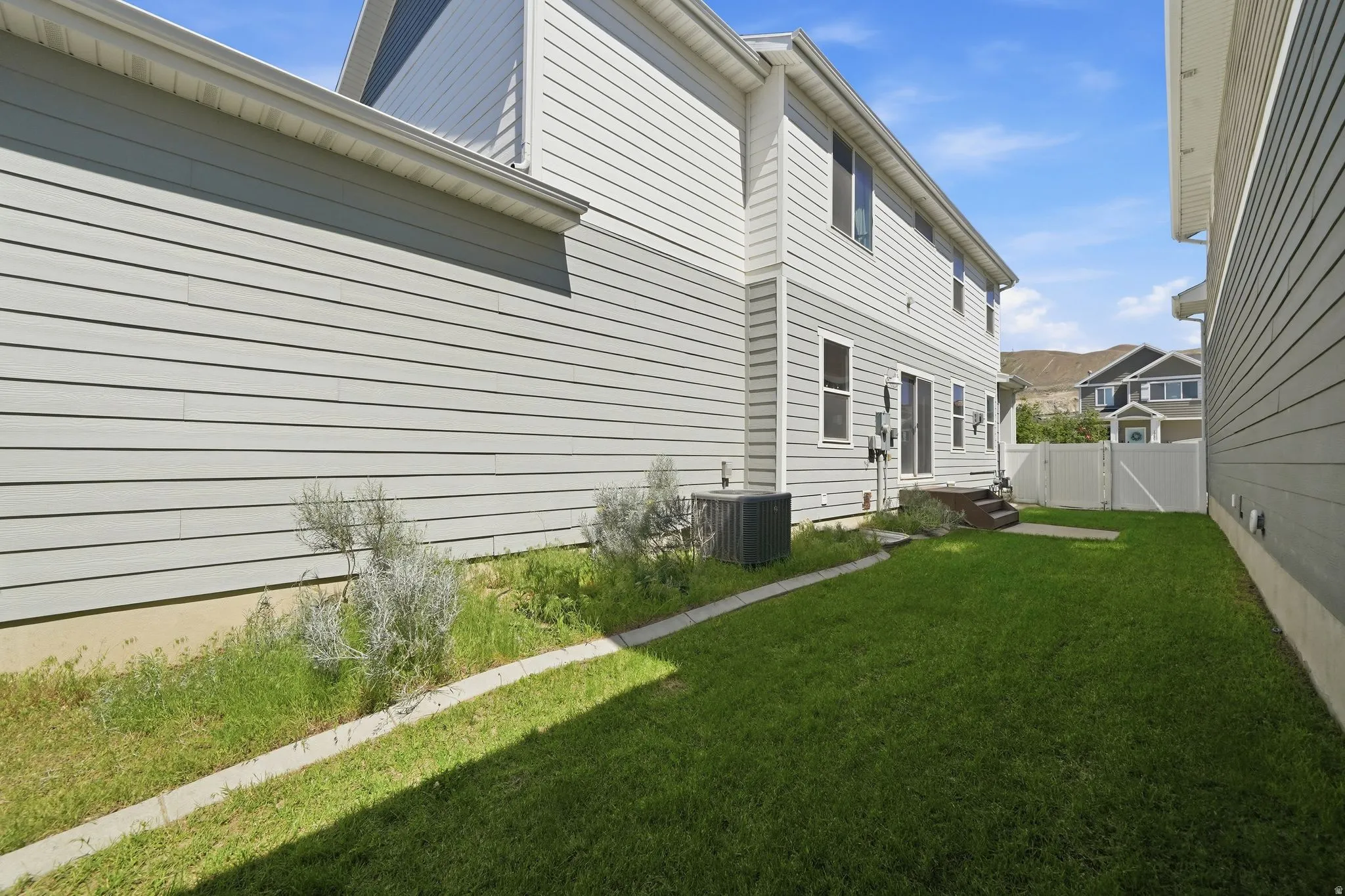 Manicured lawn area featuring a multi-level wooden deck and white privacy fencing