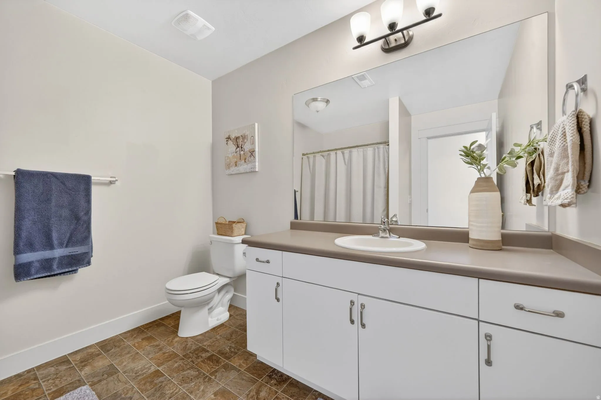 Bathroom featuring a spacious vanity with an integrated sink, white cabinetry, and matte silver hardware