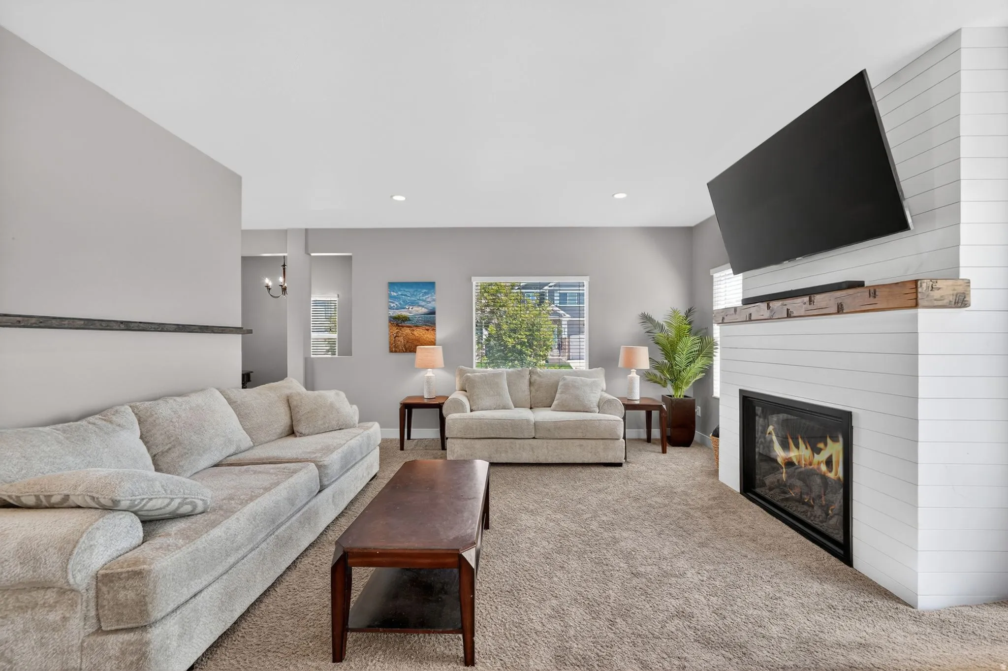 Living room featuring a shiplap fireplace with a wood mantle, recessed lighting, and a large window
