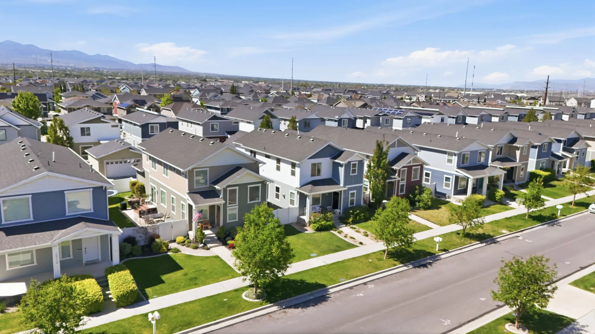 Expansive aerial perspective showcasing a residential community with numerous two-story homes featuring varied exterior siding and dark-pitched roofs