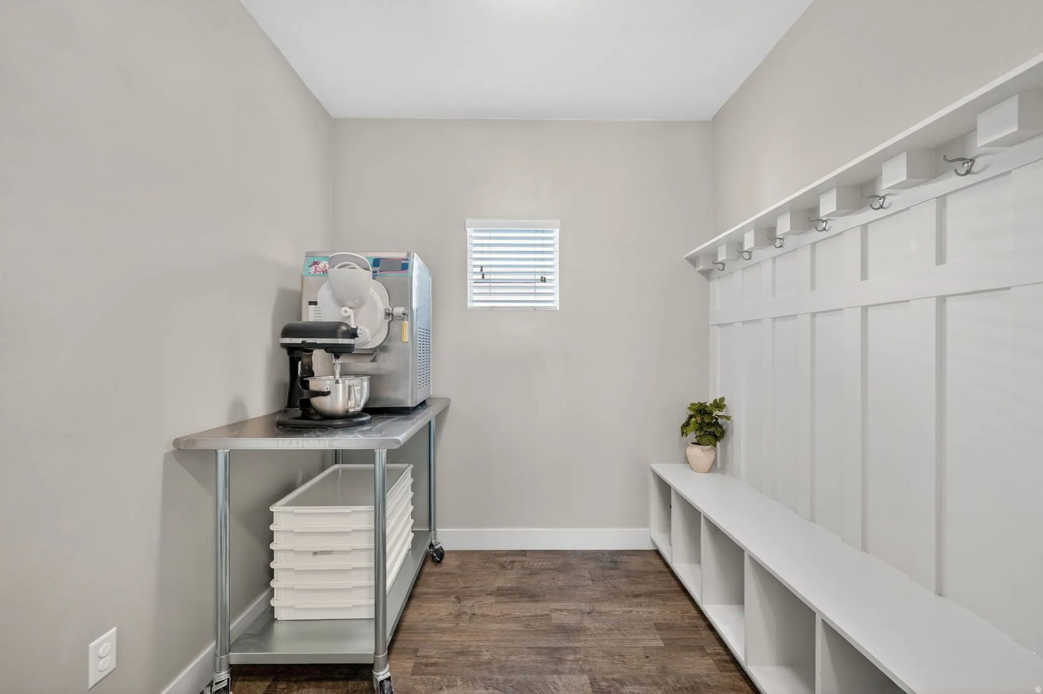 Mudroom featuring built-in white board-and-batten style storage with coat hooks and integrated cubbies