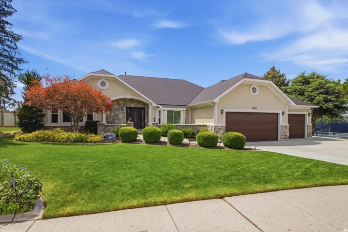 Stucco and stone exterior featuring a dark asphalt shingle roof