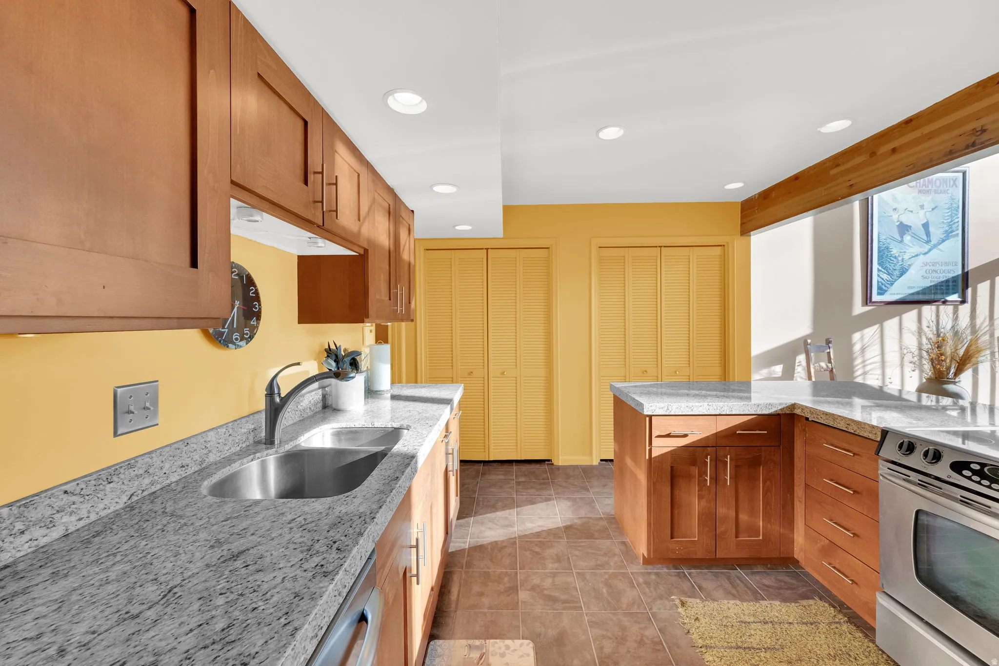 Kitchen featuring wood cabinetry with contemporary hardware, light-toned countertops, and a stainless steel sink with a gooseneck faucet