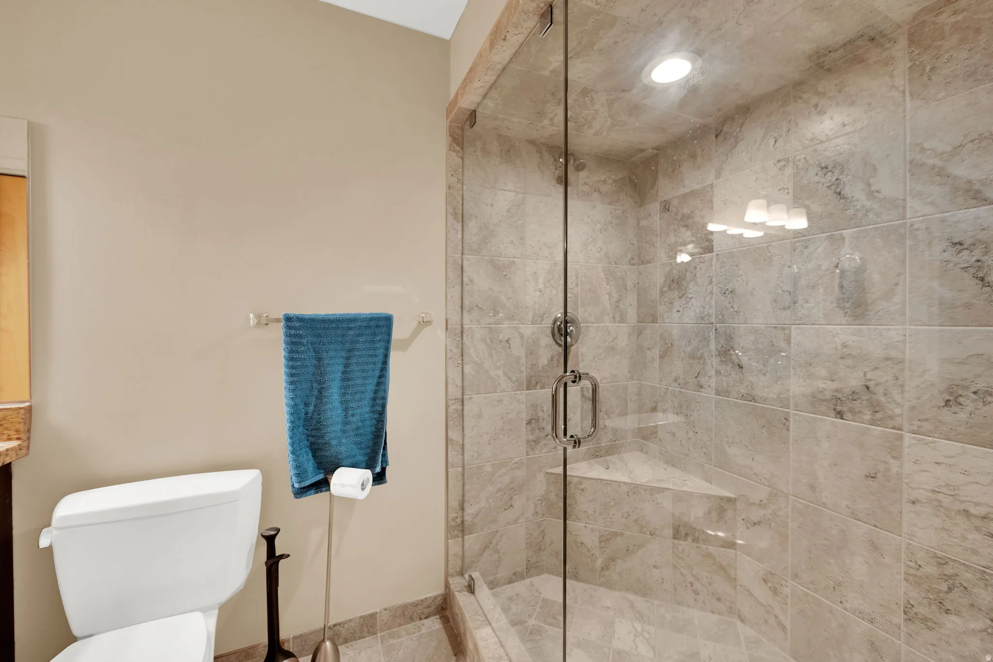 Walk-in shower with full glass enclosure, tiled walls and floor, built-in corner bench, and recessed lighting