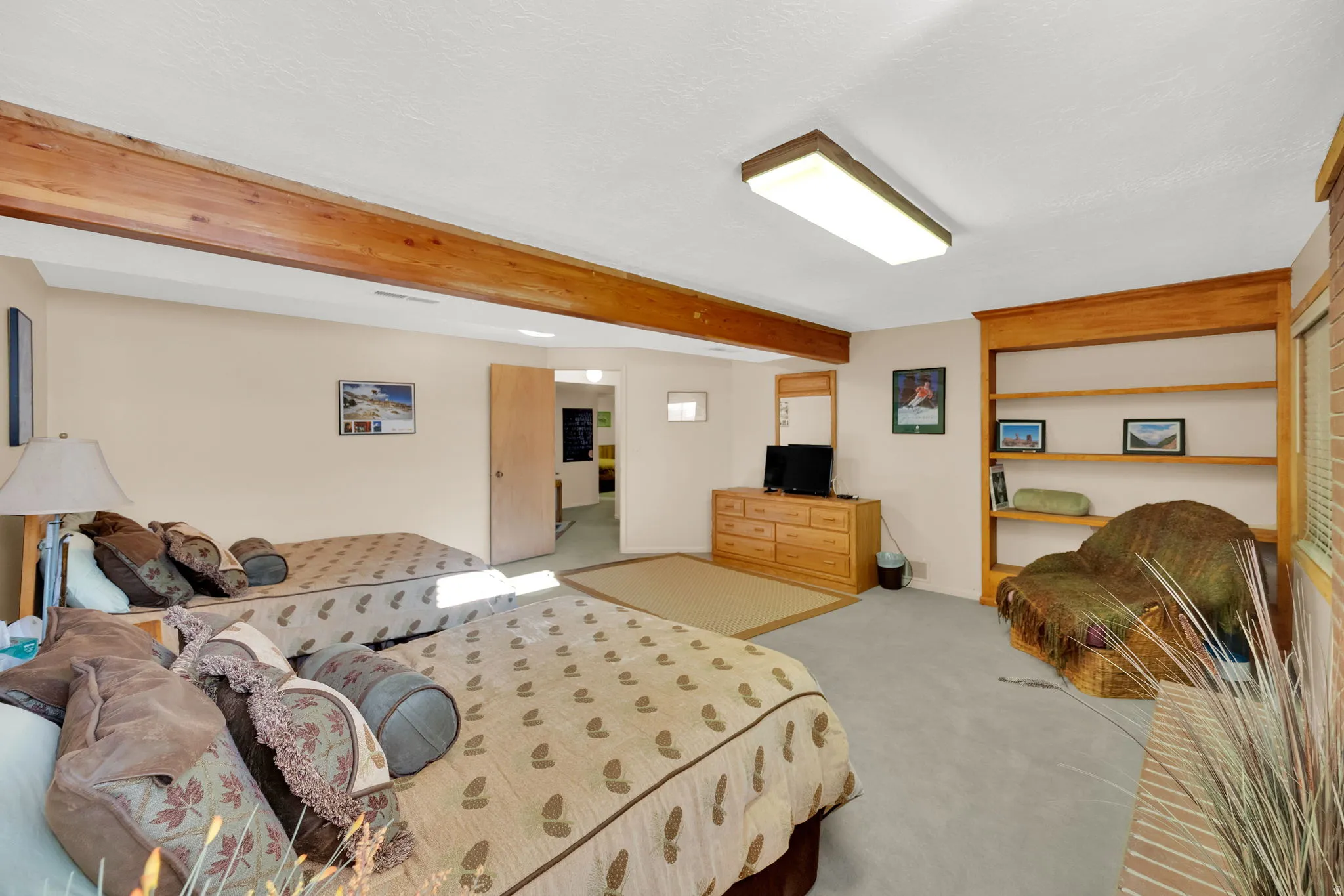 Carpeted room featuring exposed wood beams and a built-in wooden bookshelf