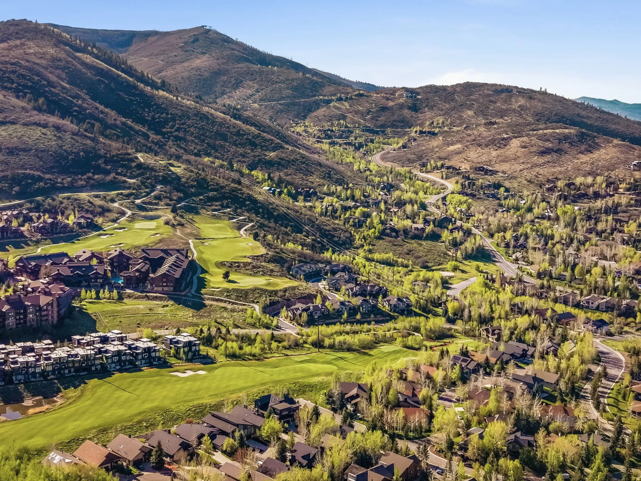 Expansive golf course community with mountain terrain, mature deciduous trees, and residential properties