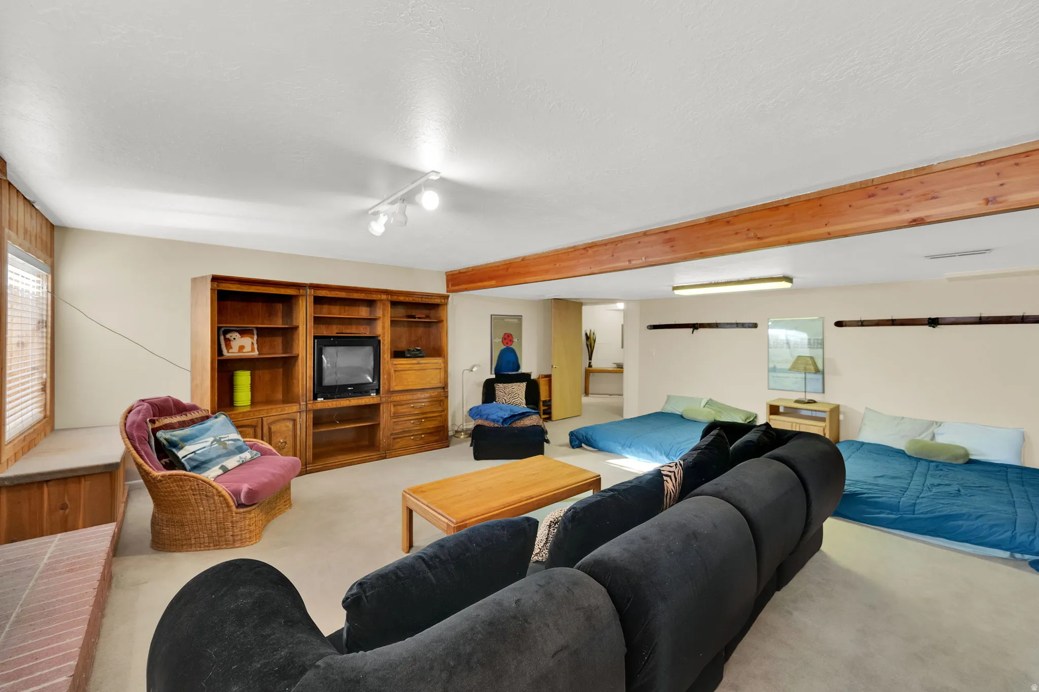 Spacious room featuring light-colored walls, recessed ceiling lighting, and a prominent wood-finish beam